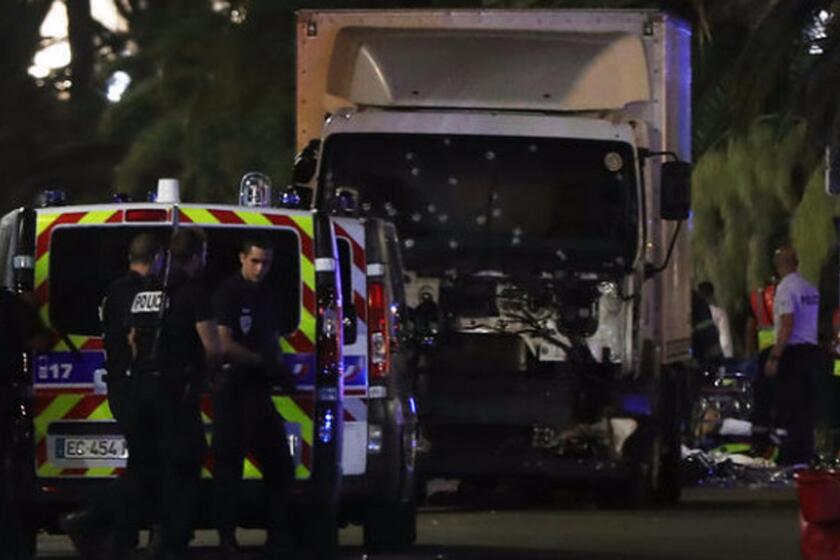 Police officers and rescue workers stand near a truck that plowed into a crowd leaving a fireworks display in Nice, France, on July 14.