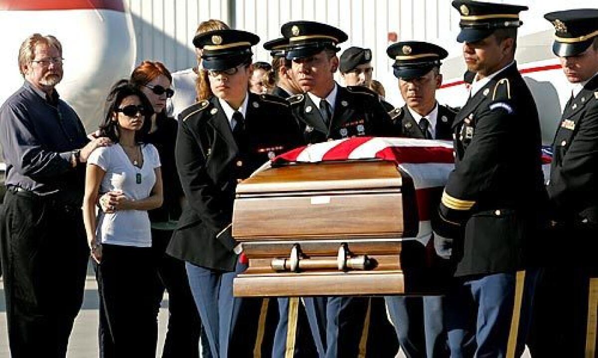 A military honor guard carries the casket past Jack Hart, left, the slain soldier's father, and Nicole Hart, his widow.