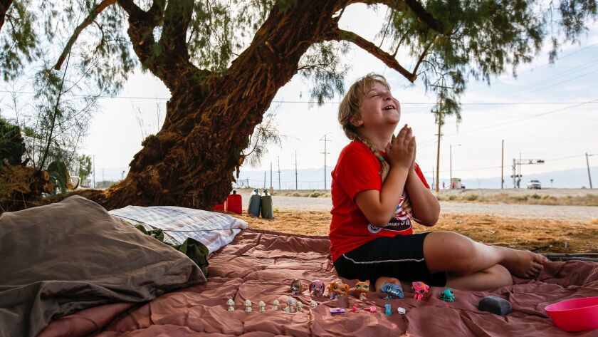 Brooke Thompson, 8, plays on the sleeping bag that her family slept in after a pair of earthquakes drove them out of their home in Trona, Calif.