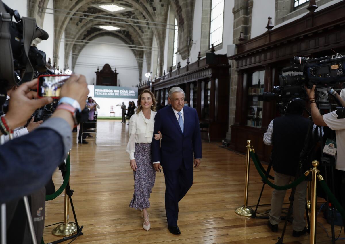 Andrés Manuel López Obrador and his wife, Beatriz Gutierrez, walk through a building.