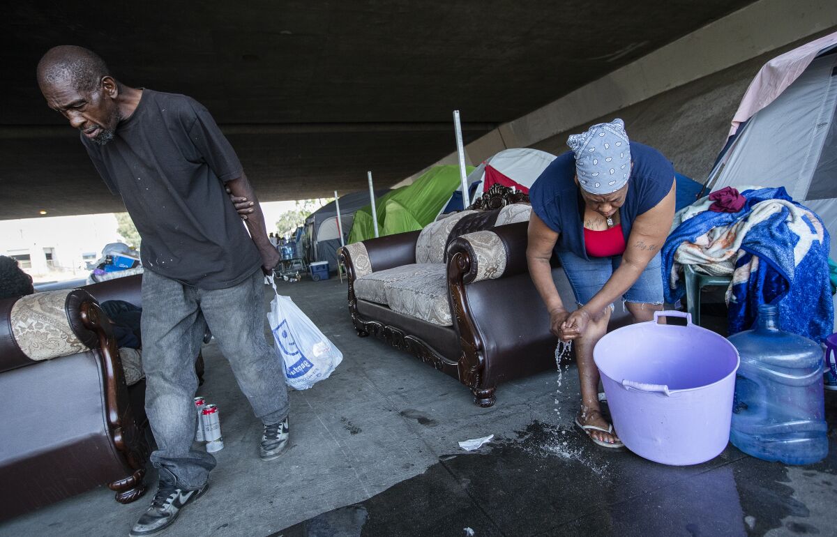 Sharrell Williams, 52, right, prepares to do her laundry at the homeless encampment in Pacoima.