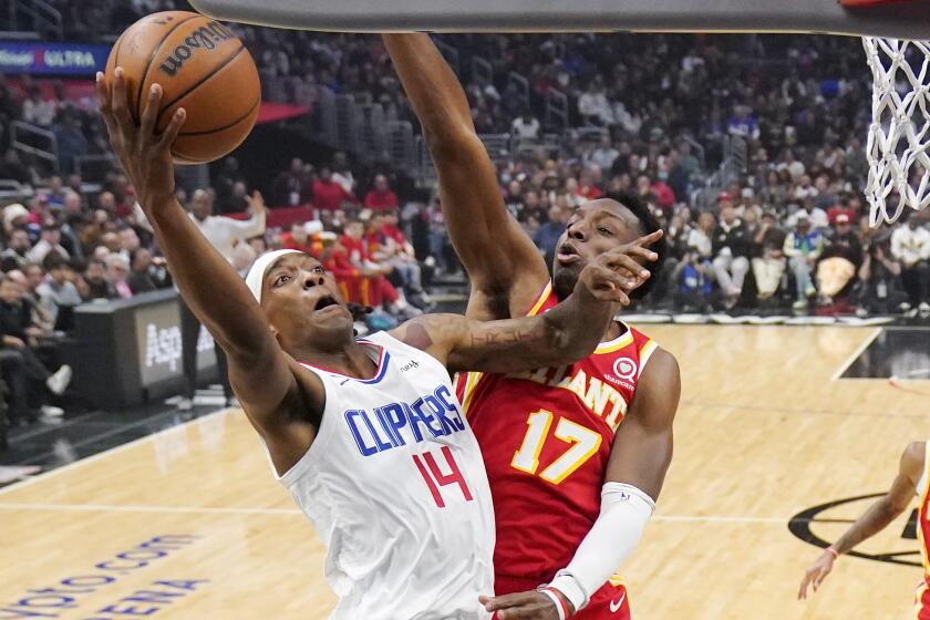 Los Angeles Clippers guard Terance Mann, left, shoots as Atlanta Hawks forward Onyeka Okongwu.