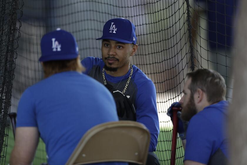 Los Angeles Dodgers outfielder Mookie Betts, center, talks with second baseman Max Muncy, right, and third baseman Justin Turner left, during spring training baseball Monday, Feb. 17, 2020, in Phoenix. (AP Photo/Gregory Bull)