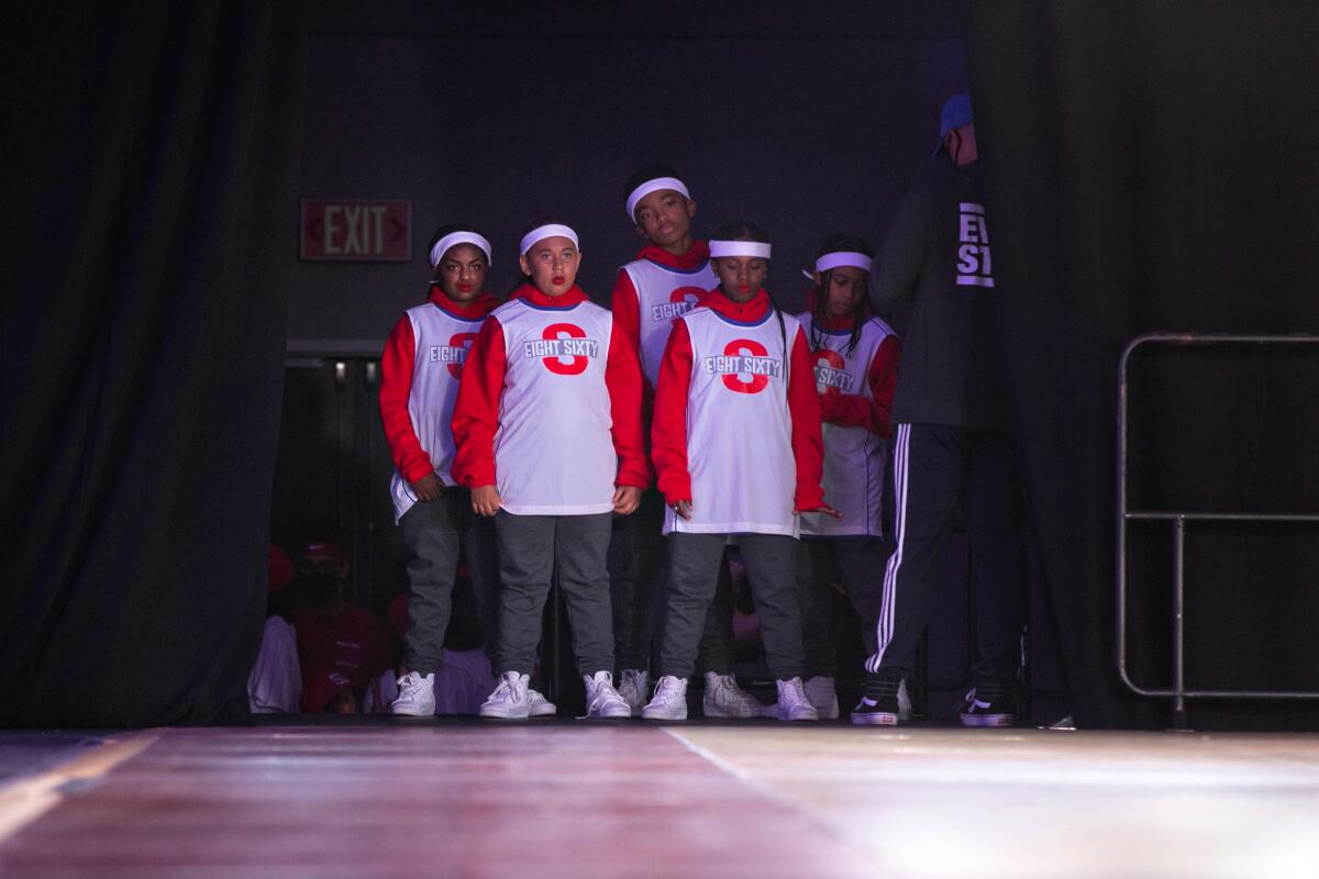A group of five young people waits in the wings to perform.