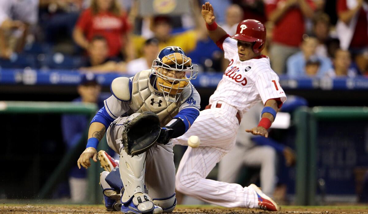 The Philadelphia Phillies' Cesar Hernandez scores past Dodgers catcher Yasmani Grandal on an RBI double during the third inning on Tuesday.