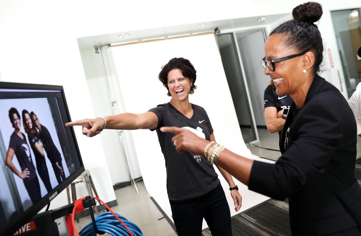  Julie Uhrman and Renata Simril laugh and point at a monitor.