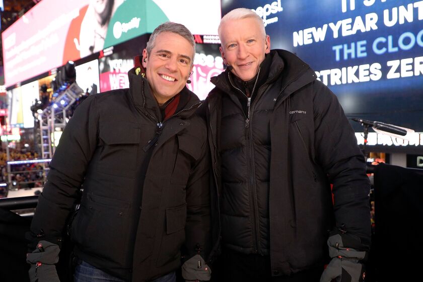 Two men smiling in winter coats and gloves in Times Square, New York