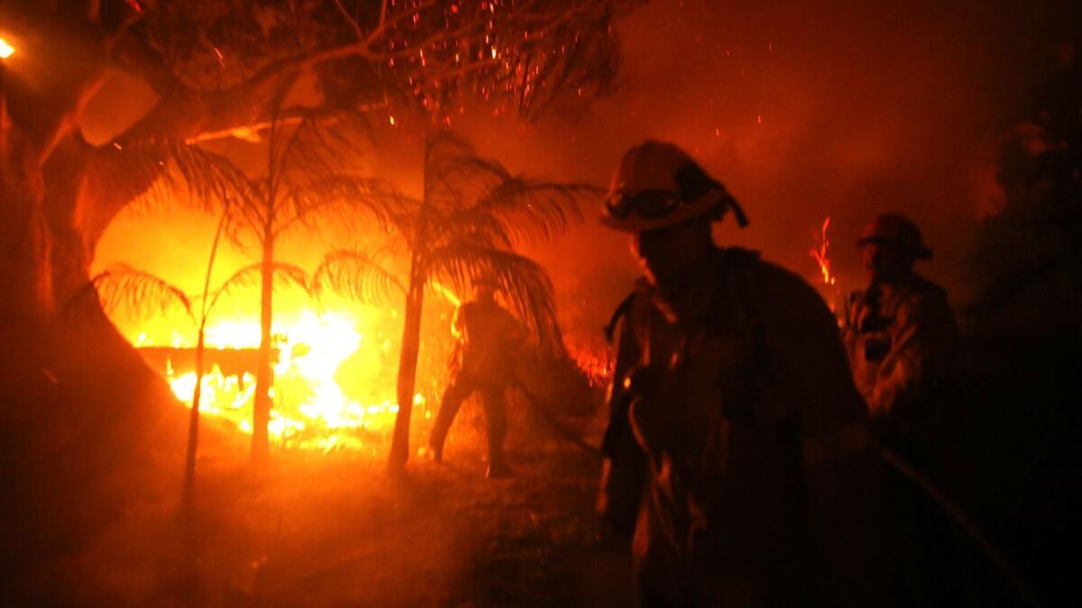A firefighter tries to put out the flames on a burning home from the Woolsey fire on Dume Drive in Malibu in November. Fire officials warn that California could see even more blazes this year.