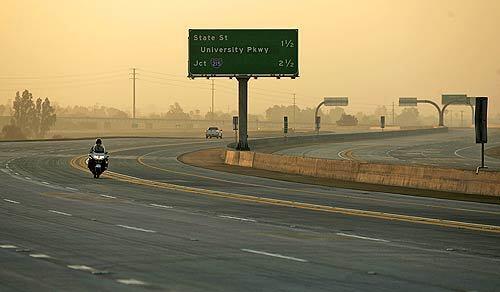 A CHP officer cruises along an empty stretch of the 210 Freeway that opened to motorists Tuesday.