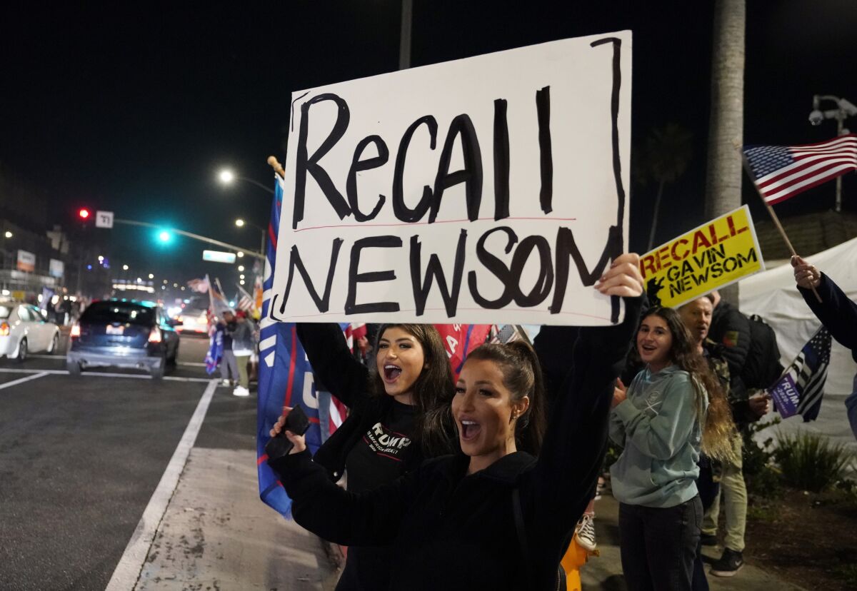  Trump supporters carry signs calling for the recall of California Gov. Gavin Newsom in Huntington Beach in November.