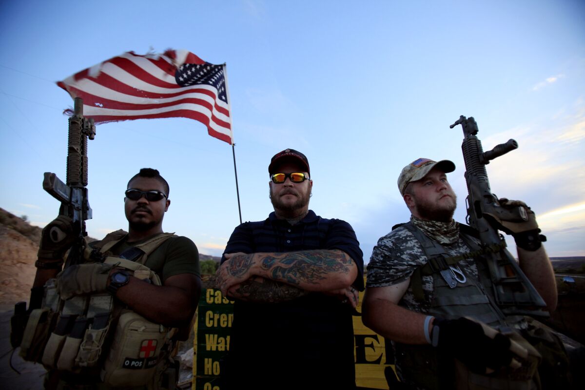 Army veteran Jason Bullock, left, "Booda," middle, and "Socks" act as "personal security" guards at the entrance to Cliven Bundy's ranch in Bunkerville, Nev., on July 20, 2014.
