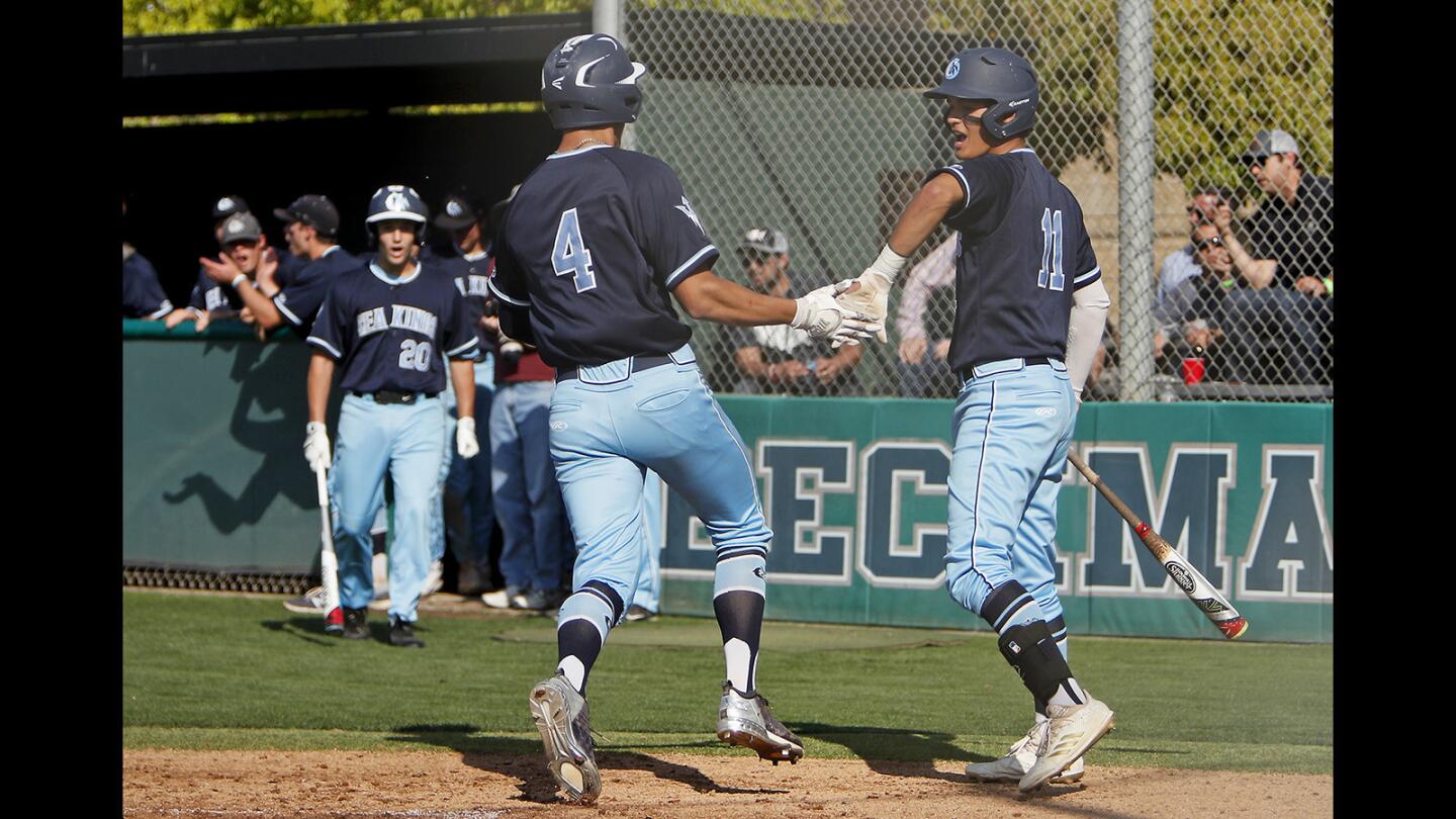 Corona del Mar High's Chazz Martinez (4) is congratulated by Reece Berger (11) after scoring against Beckman during the fourth inning in a Pacific Coast League game in Irvine on Tuesday, April 3.
