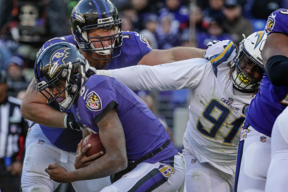 The Chargers' Justin Jones grabs Ravens quarterback Lamar Jackson during their AFC playoff game in January.