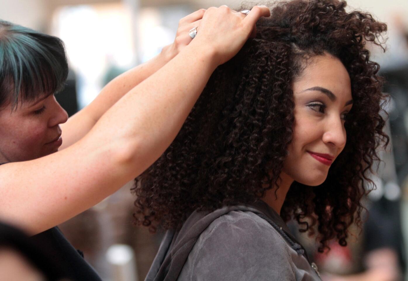 Hair and makeup artist Jaime Leigh-McIntosh, left, ads a layer of pull-away hair for Monica Ramirez, as she prepares to rehearse a fight scene.