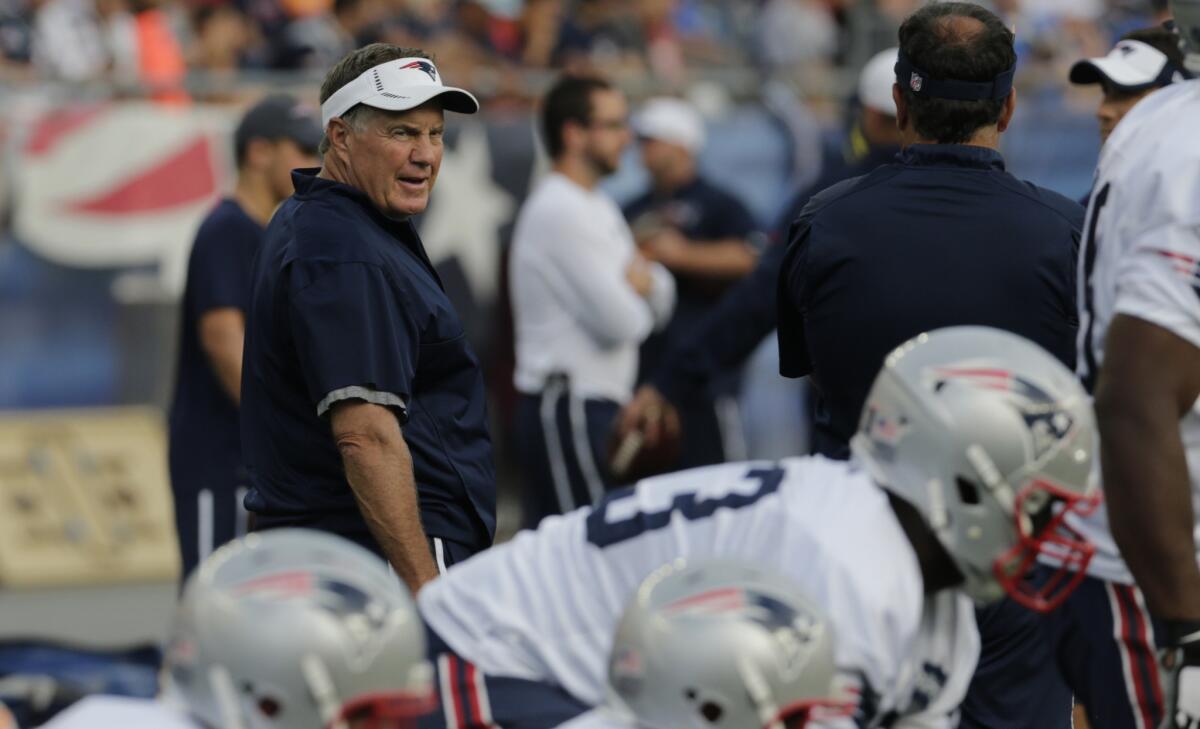 Patriots Coach Bill Belichick watches players warm up for a workout at training camp on Aug. 5.