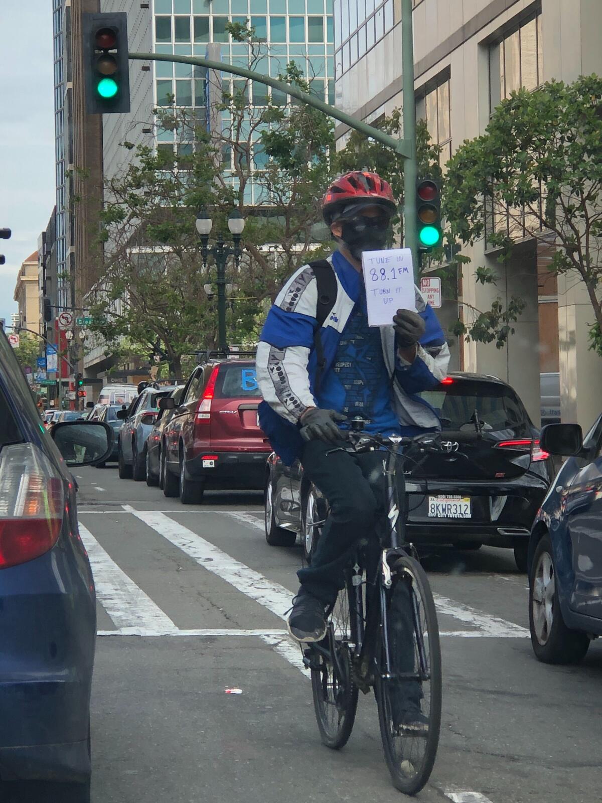 A cyclist directs protesters to tune to 88.1 FM during Sunday's caravan through Oakland.