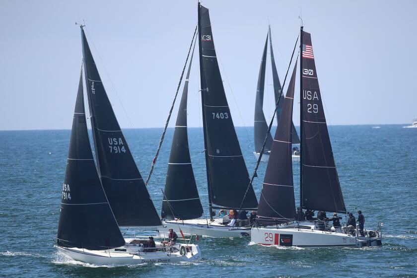 Three racers including crews on Double Down, Radical Departure, and Dart, from left, take off from the starting line of the 76th, Newport to Ensenada International Yacht Race outside the Balboa Pier from Newport Beach on Friday.
