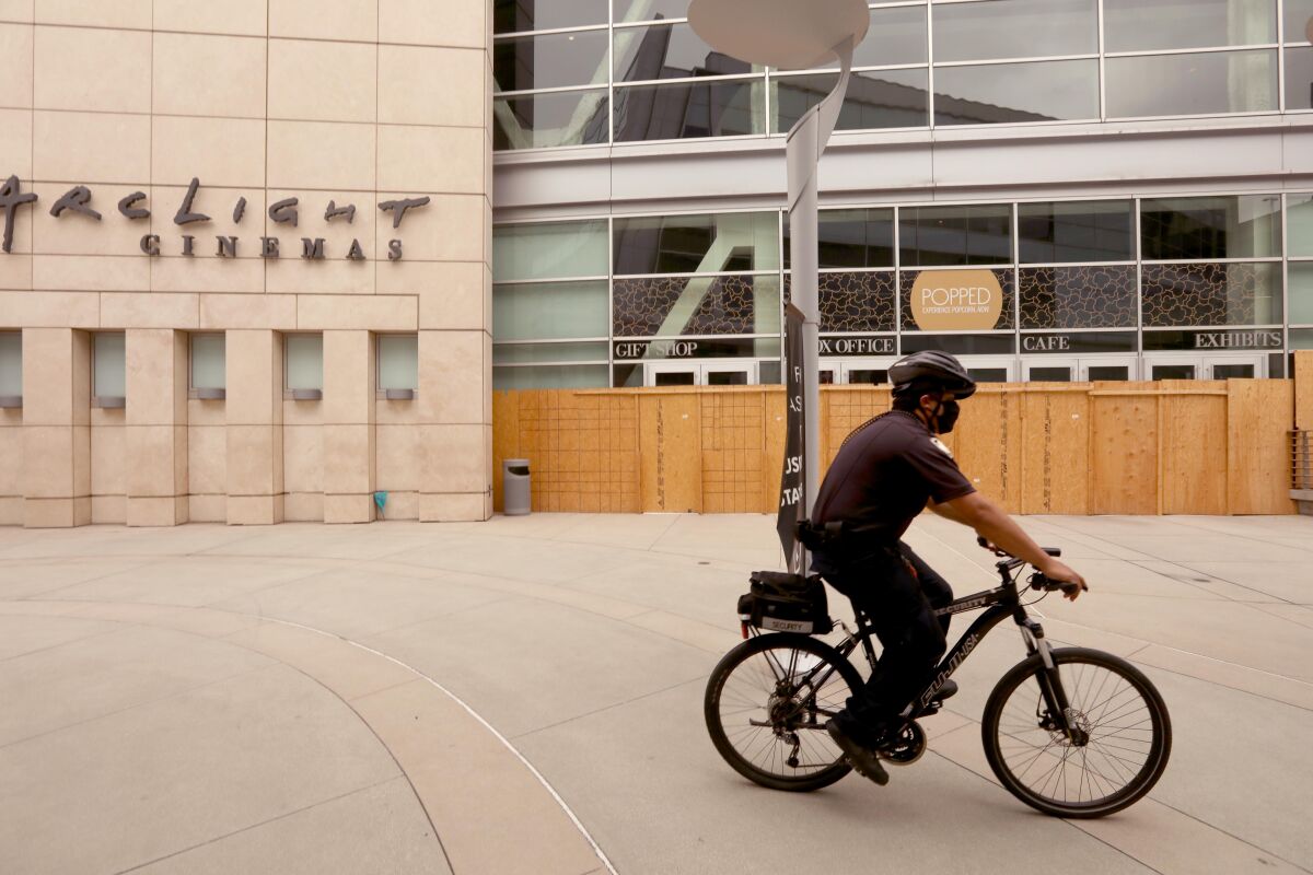 A security guard on a bicycle rides past the shuttered ArcLight Cinemas in Hollywood.