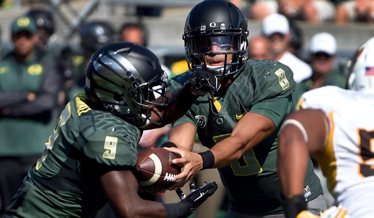 Oregon quarterback Marcus Mariota prepares to hand off to Byron Marshall during a game against Wyoming earlier this season in Eugene.
