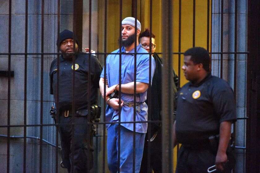 Officials escort "Serial" podcast subject Adnan Syed from the courthouse following the completion of the first day of hearings for a retrial in February.