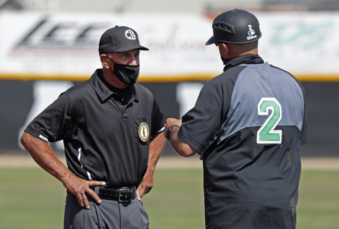 Umpire and coach chat on the field.