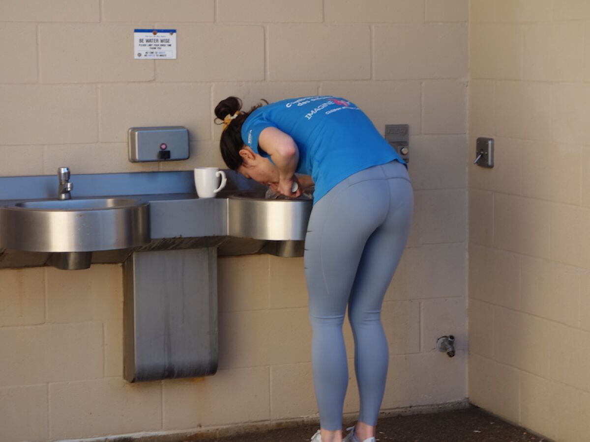 A person uses a sink at the Kellogg Park restroom facility in La Jolla Shores after emerging from a van parked nearby.