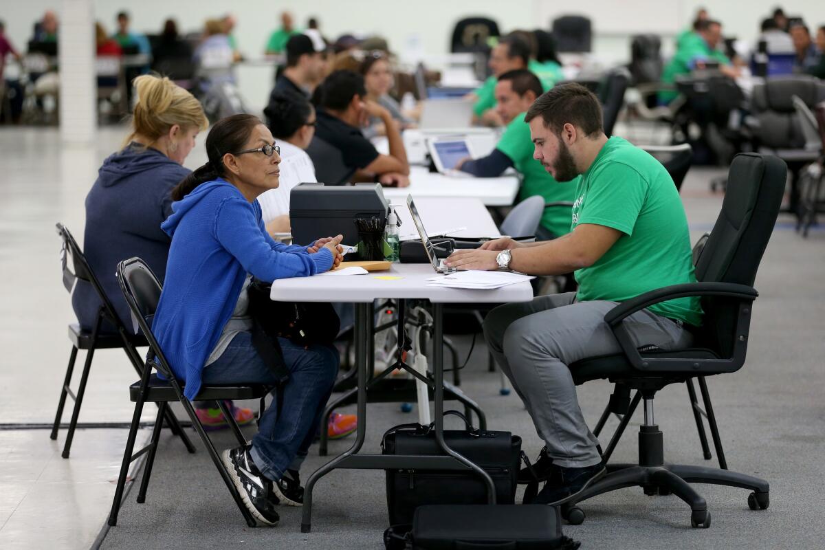 Juana Rivera, left, speaks with Fabrizzio Russi, an agent from Sunshine Life and Health Advisors, as they discuss plans available under the Affordable Care Act at a store set up in the Mall of the Americas in Miami on Dec. 15.