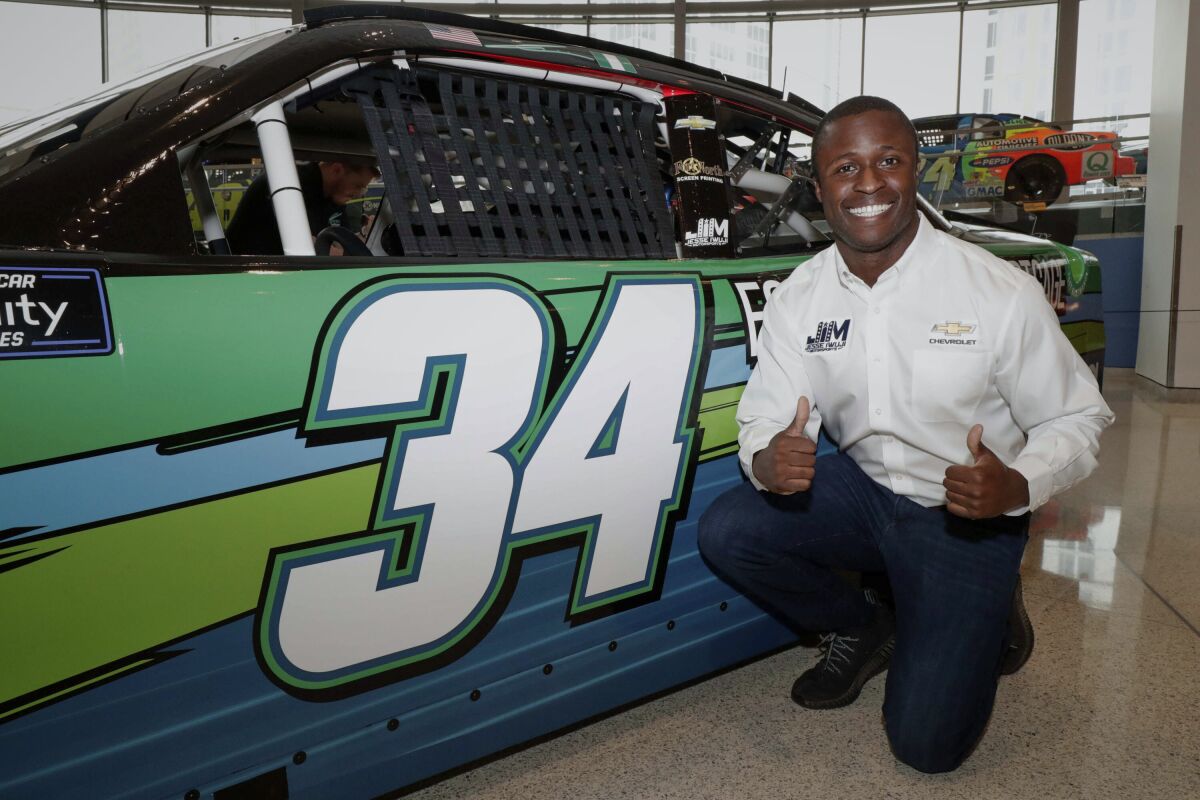 NASCAR driver Jesse Iwuji poses with the No. 34 Chevrolet Camaro SS he will drive in the upcoming 2022 NASCAR Xfinity Series season at the NASCAR Hall of Fame in Charlotte, N.C., Monday, Feb. 7, 2022. Iwuji will run his first full season in NASCAR with backing from Pro Football Hall of Famer Emmitt Smith and General Motors.(Garry Eller/HHP for Chevy Racing via AP)