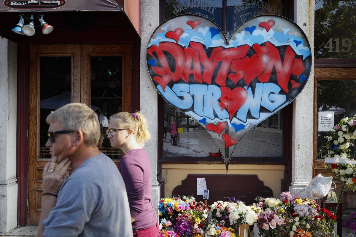 FILE - In this Aug. 7, 2019 file photo, pedestrians pass a makeshift memorial for the slain and injured victims of a mass shooting that occurred in the Oregon District in Dayton, Ohio. The six officers who shot and killed an active shooter in Dayton 32 seconds after the man’s assault began have offered brief comments about that night for the first time. The officers’ remarks are coming on the eve of the third anniversary of the massacre that killed nine and wounded more than two dozen. (AP Photo/John Minchillo, File)