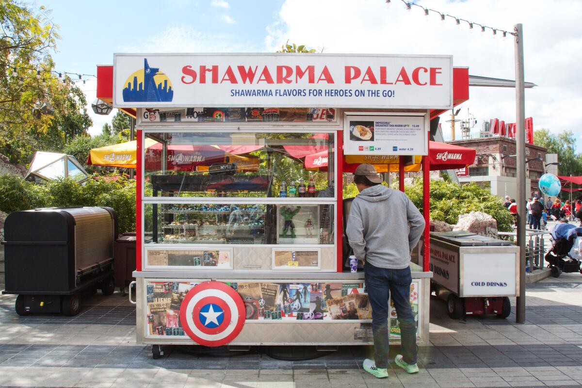 A customer stands ready to order at Shawarma Palace, a silver New York-style street cart.