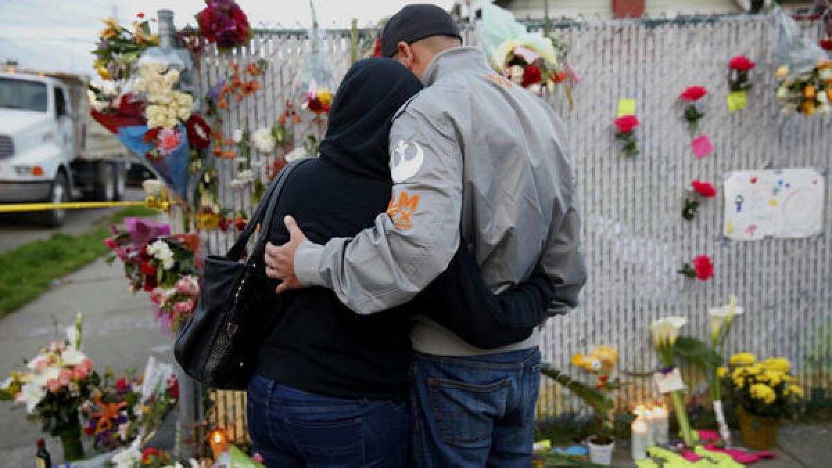 Mourners hug next to flowers near the site of the warehouse fire.