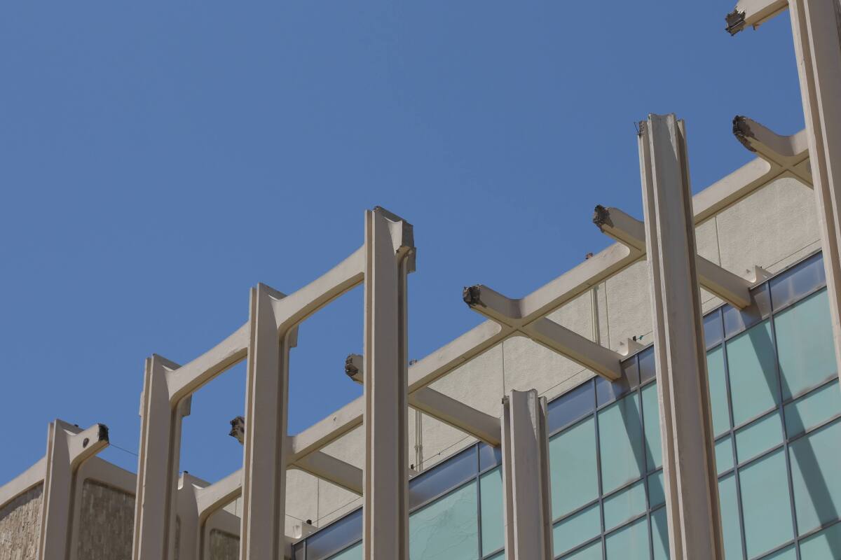 The top edge of LACMA's columned façade — with pieces missing — is seen against a blue sky