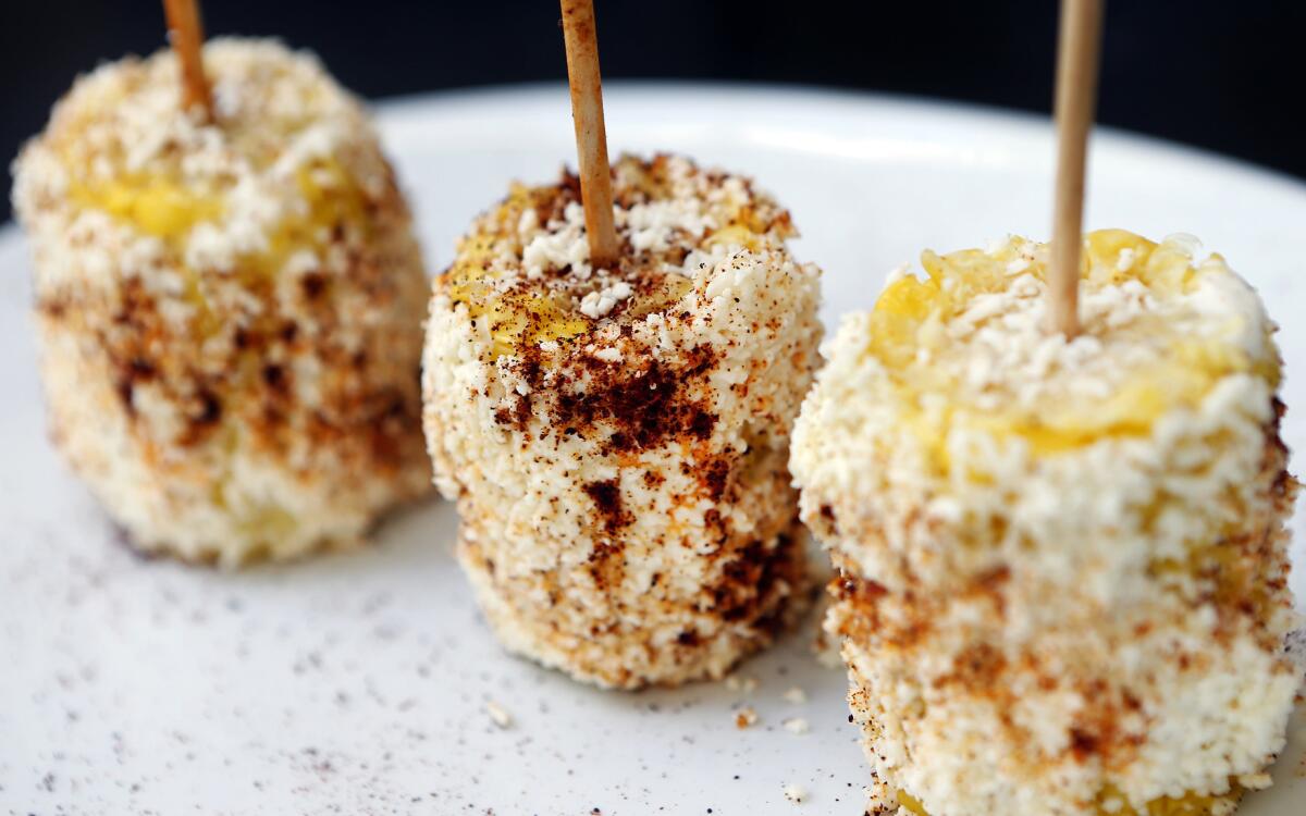 Classic elote: cobs of corn on skewers, rolled in cheese, mayonnaise and cayenne pepper.