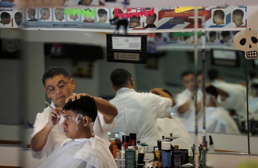 Edgar Mendoza cuts hair at Gabriel's Barber Shop, a business he owns and operates in the West Adams district of Los Angeles.