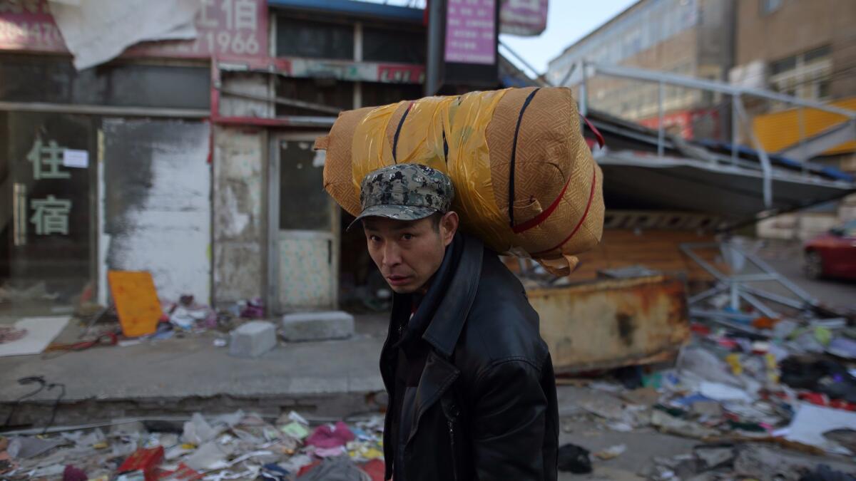 A Chinese migrant worker carries his belongings as he leaves Xinjian village in Beijing's Daxing district on Nov. 24, 2017.