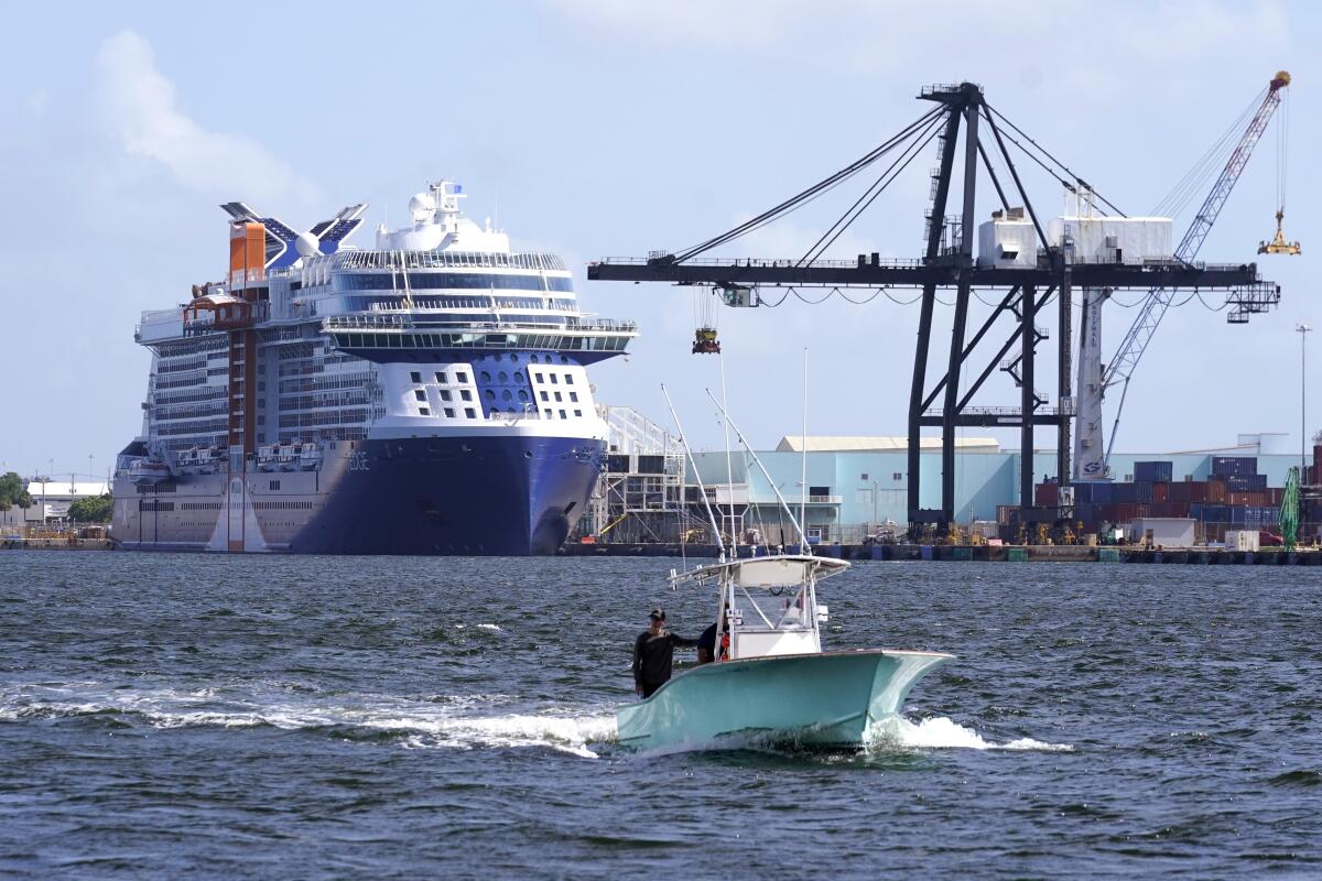 A small boat passes near a docked cruise ship.