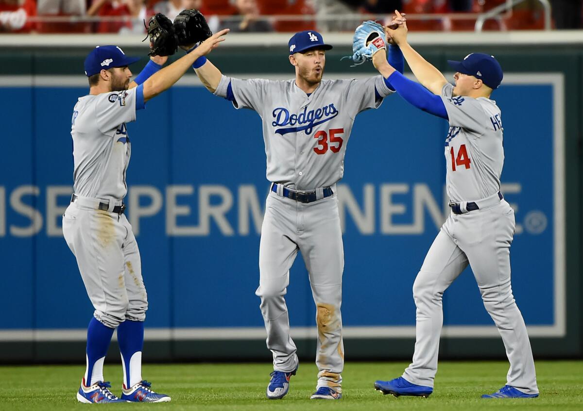 Dodgers outfielders Chris Taylor (3), Cody Bellinger (35) and Enrique Hernandez (14) celebrate after the final out of Game 3 of the NLDS to defeat the Washington Nationals 10-4 at Nationals Park on Oct. 06 in Washington, DC. 