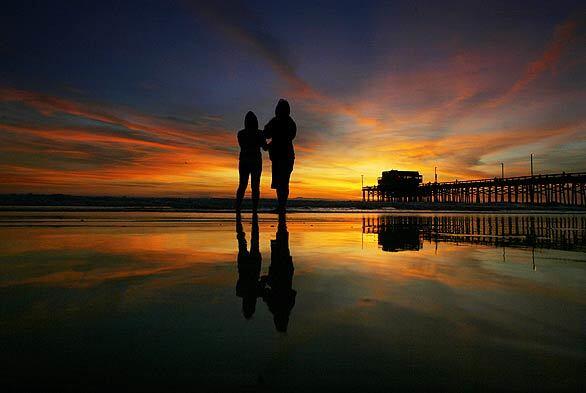 DAY'S END: Newport Beach visitors are silhouetted by the autumn sunset.