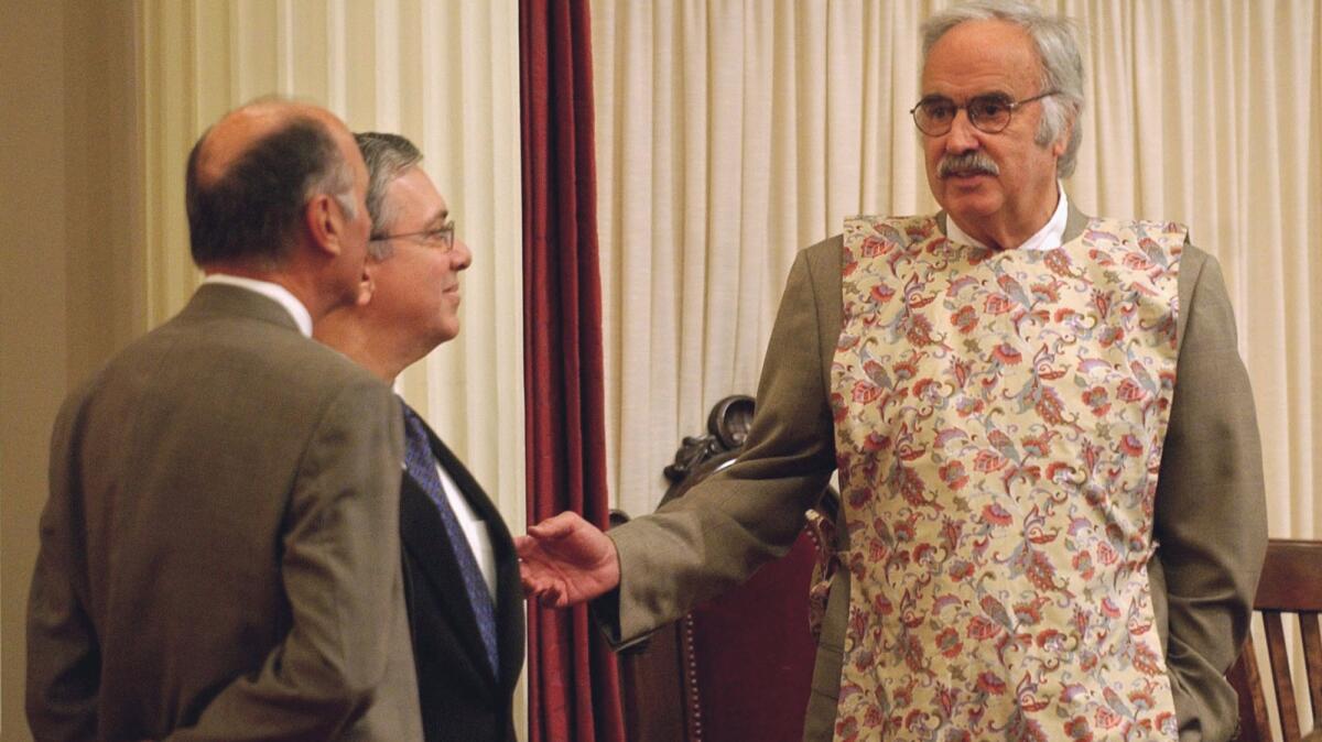 Wearing a kitchen apron to protest a pastor's remarks in 2004, then-Senate President Pro Tem John Burton, right, talks with Senate Minority Leader Dick Ackerman, RFullerton, center, and Sen. Charles Poochigian, RFresno.