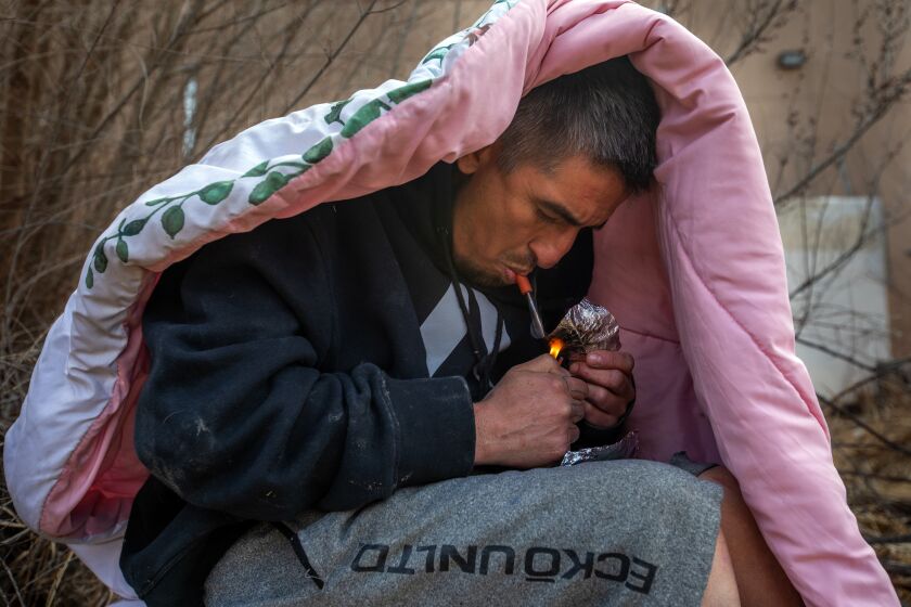 Espanola, NM - March 08: Sitting beneath a blanket to block the wind from extinguishing the flame from his lighter a man smokes fentanyl on Wednesday, March 8, 2023, in Espanola, Espanola, NM - March 08: Sitting beneath a blanket to block the wind from extinguishing the flame from his lighter - a man smokes fentanyl on Wednesday, March 8, 2023, in Espanola, NM. In a one-year period ending in June 2022, Rio Arriba County reported an estimated 50 fatal overdoses, giving it the highest rate in New Mexico. It was nearly four times the national rate of about 33 per 100,000. (Francine Orr / Los Angeles Times)