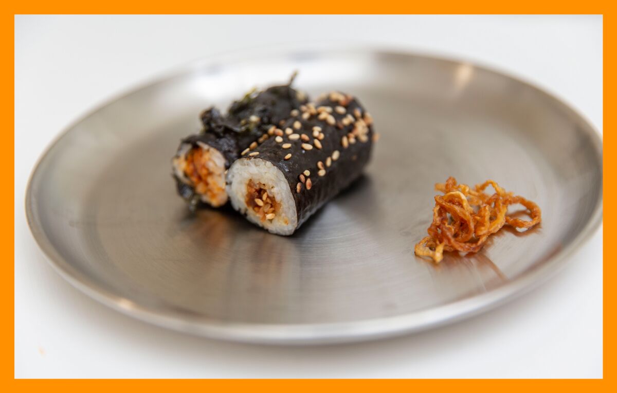 Two seaweed-wrapped rice rolls on a metal plate