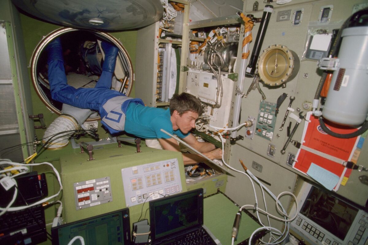 His feet anchored in a tunnel hatchway, cosmonaut Sergei Krikalev works on the International Space Station on Dec. 6, 2000.