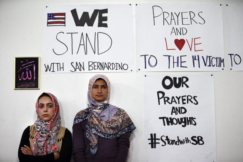Khadija Zadeh, left, and Noora Siddiqui stand next to signs while listening to a speech during an interfaith memorial service at the Islamic Community Center of Redlands, Sunday, Dec. 6, 2015, in Loma Linda, Calif. The memorial service was held to honor the victims of Wednesday's shooting rampage that killed 14 people in San Bernardino, Calif. (AP Photo/Jae C. Hong)