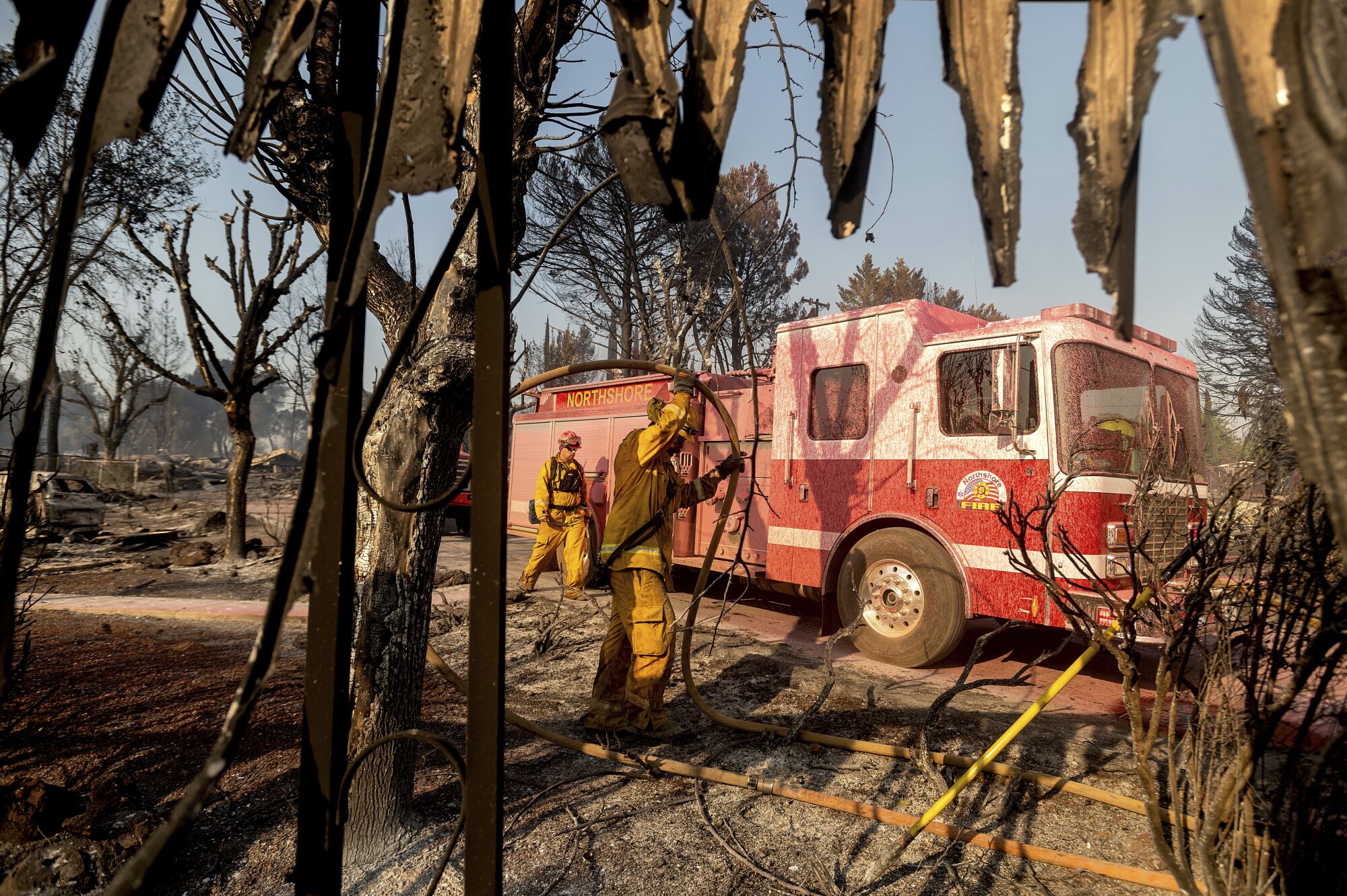 Firefighters mop up at Cache Creek Mobile Home Estates where the Cache fire leveled dozens of residences in Clearlake.