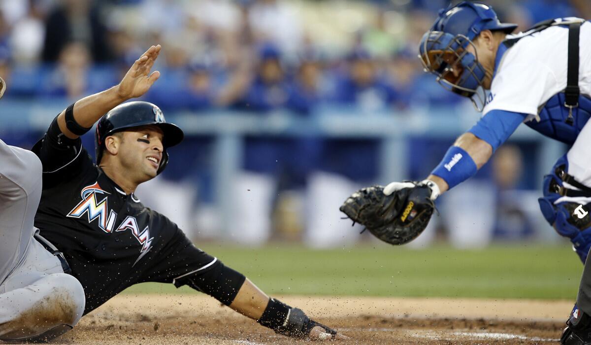 Miami Marlins' Martin Prado, left, slides under the tag by Dodgers catcher A.J. Ellis to score on a base hit by Marcell Ozuna during the first inning on Wednesday.