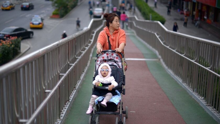 A woman pushes a baby carriage on an overpass in Beijing. China dropped its one-child policy in 2016 as the country's population began to age. But so far the birthrate continues to fall.