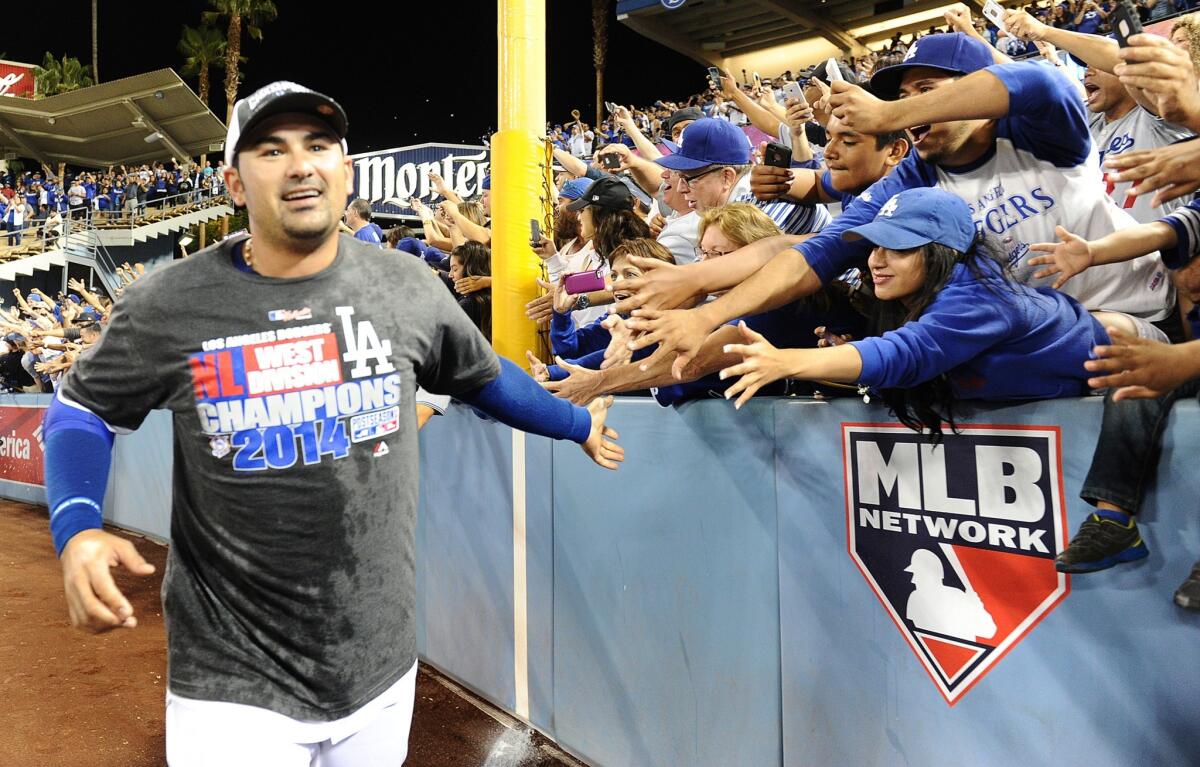 Dodgers first baseman Adrian Gonzalez slaps hands with fans as he runs around the outfield of Dodger Stadium on Sept. 24 while celebrating the club's National League West title.