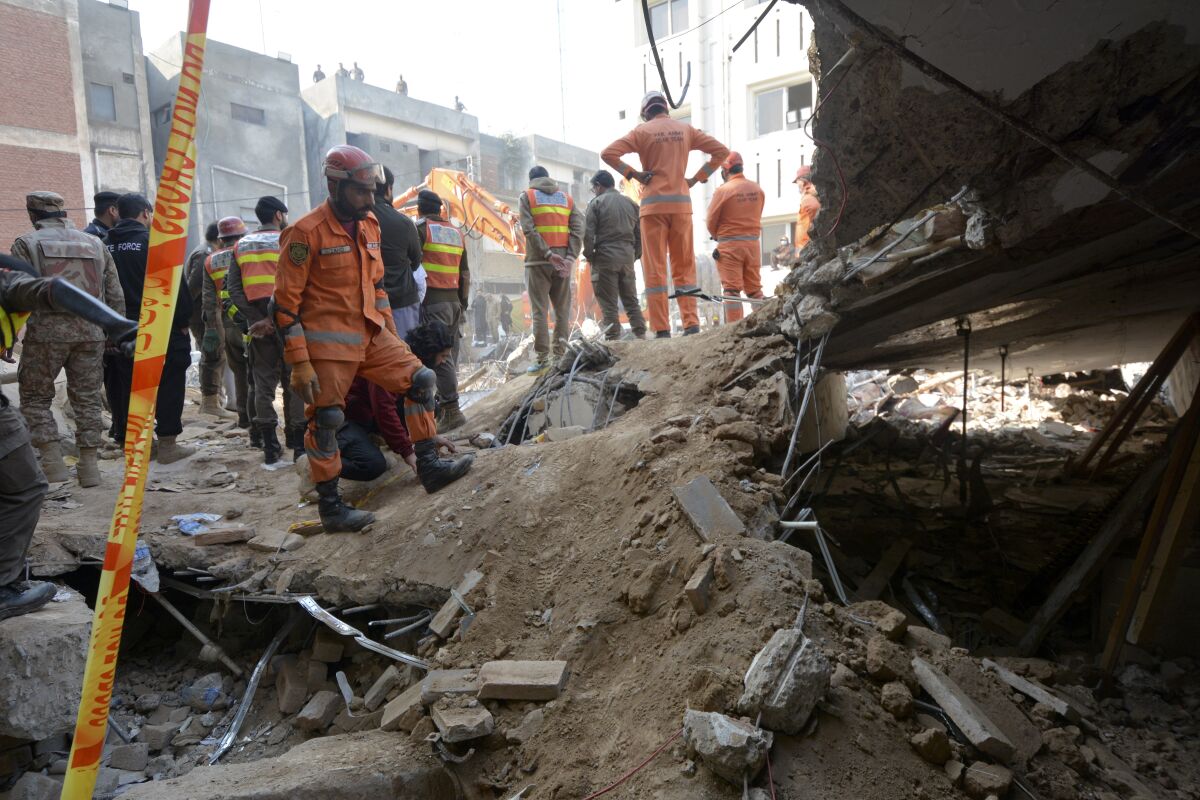 Rescue workers atop rubble at site of suicide bombing in Peshawar, Pakistan