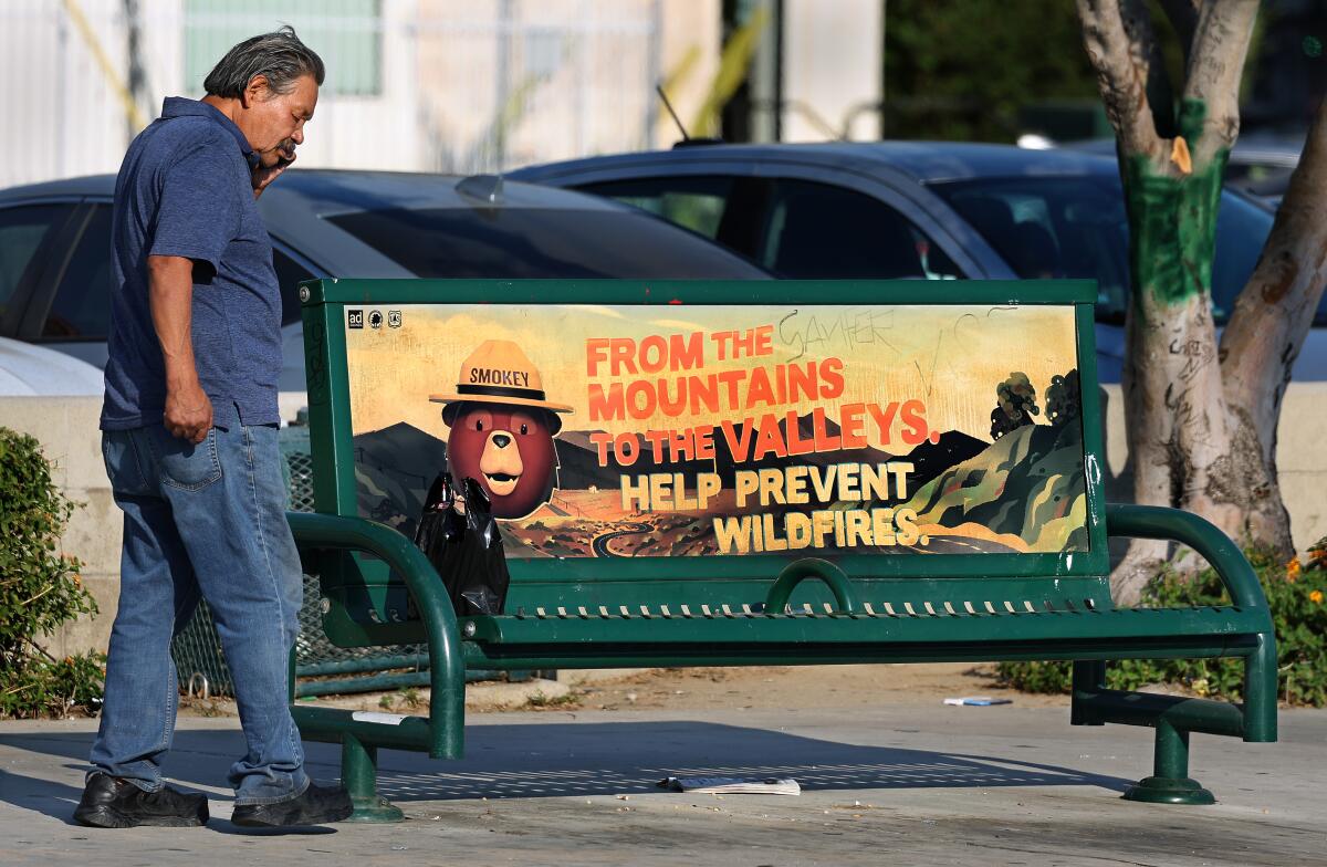 A man waits at a Metro bus stop with no shade