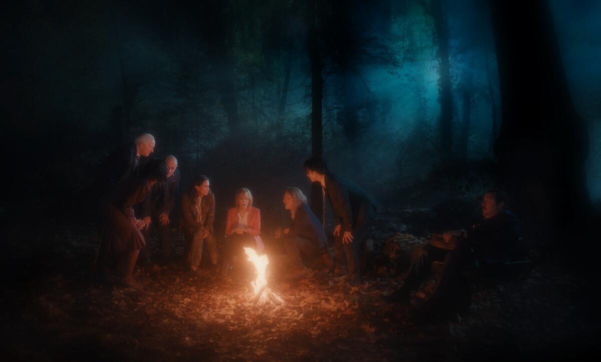 World leaders gather around a fire in the woods.